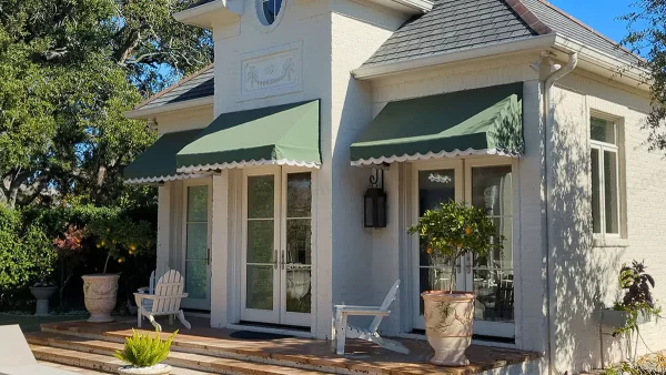 Green hood awnings with custom double valance over French doors on white brick home